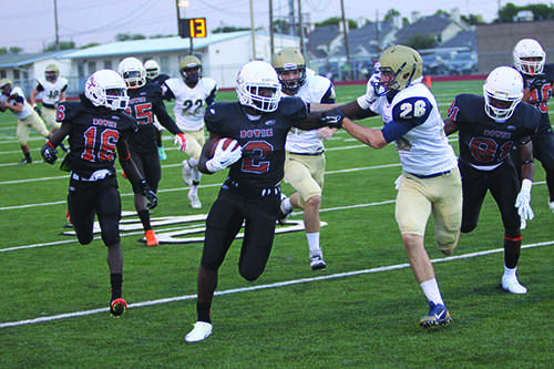 WR Anthony Hawkins carries the ball while stiff arming a Jesuit defender.