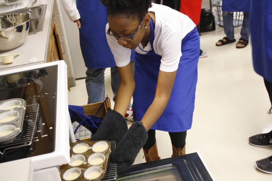 Kanyinsola Akingbade in Nutrition and Wellness class is participating in Cupcake Wars in the 6th period class. Akingbade is putting cupcake batter in the oven to bake her goodies. 